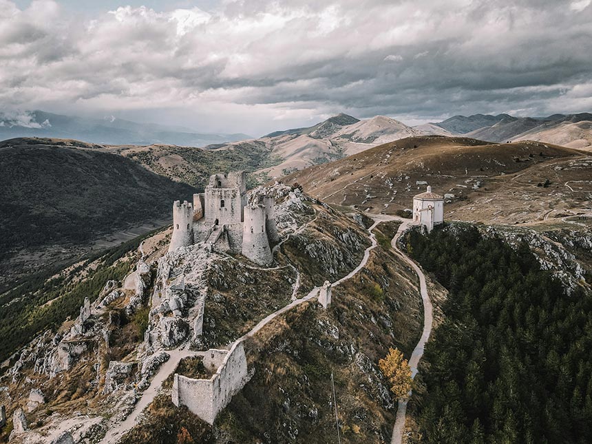 Fotografía tomada con un dron de un paisaje de montañas donde se ve un gran castillo