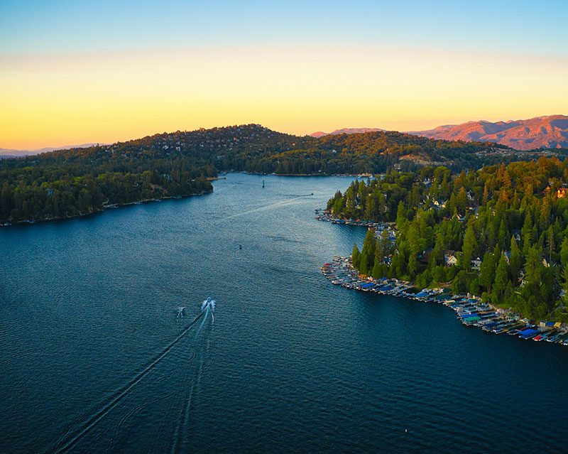 Fotografía aérea de un lago rodeado de un verde bosque y con un barco navegando